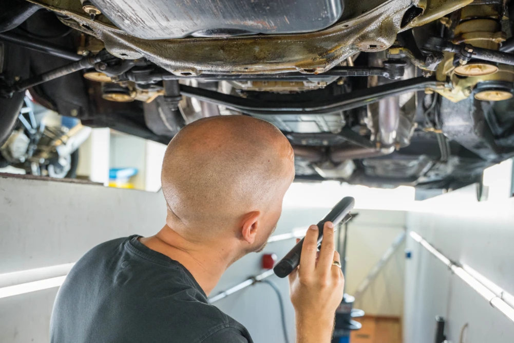Prüfingenieur untersucht Fahrzeug von unten bei der Hauptuntersuchung bei Hett und Hemm